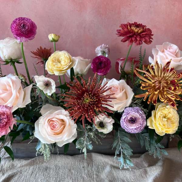 Mixed bouquet of pale roses and colorful blooms in a low arrangement