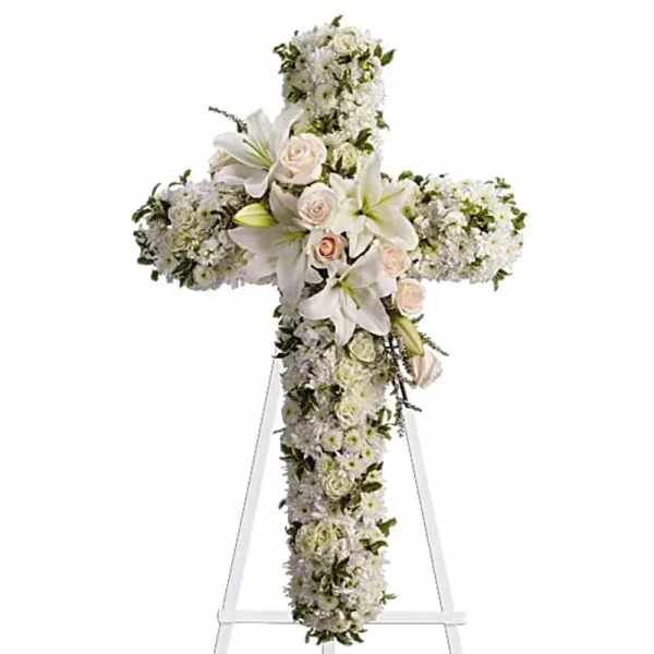 White floral cross arrangement with lilies and roses on a stand
