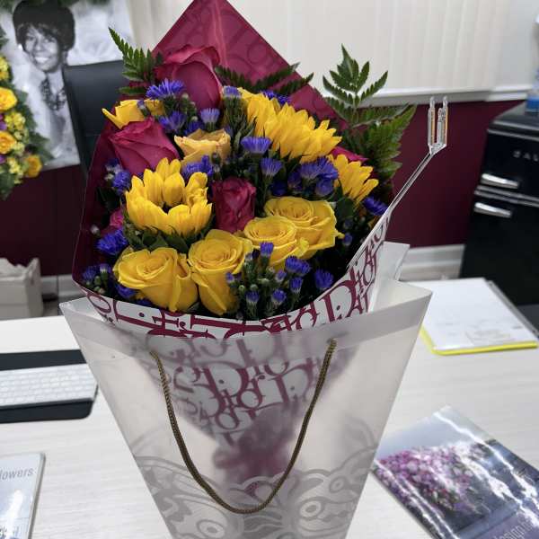 Bouquet of yellow and magenta roses with purple filler flowers in a gift wrap