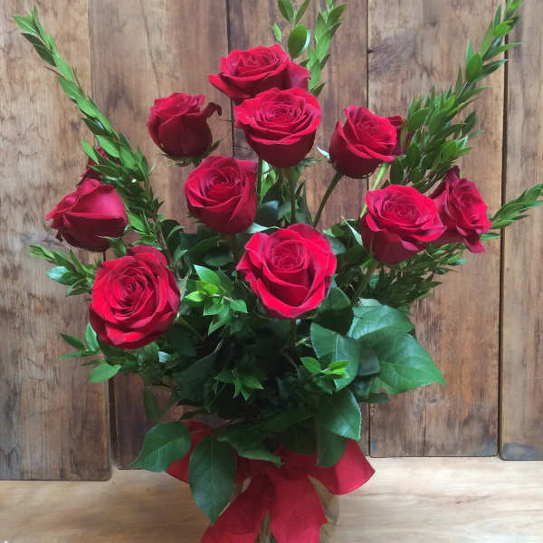 Bouquet of red roses in a clear glass vase with a red ribbon