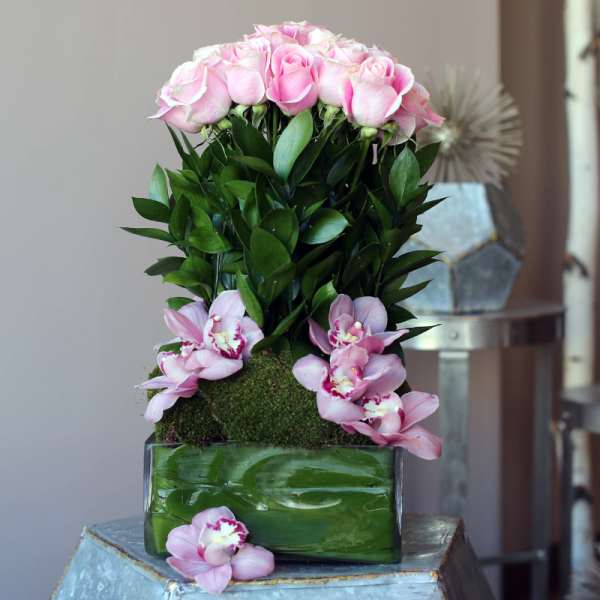 Pink roses and orchids arranged in a glass vase