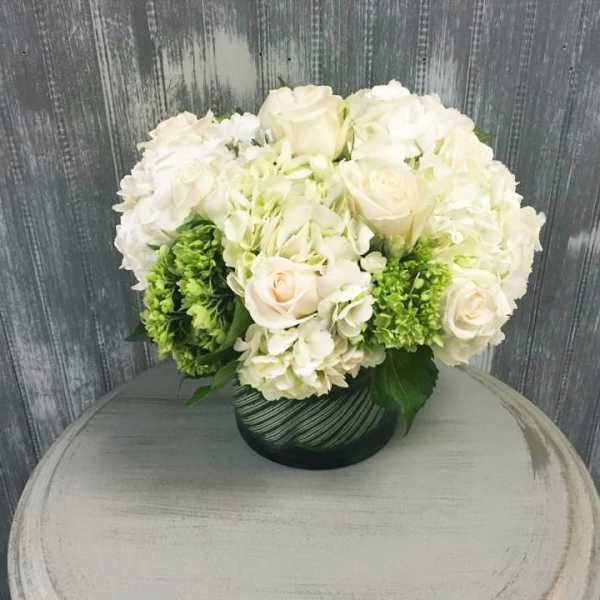 White roses and hydrangeas in a dark glass vase
