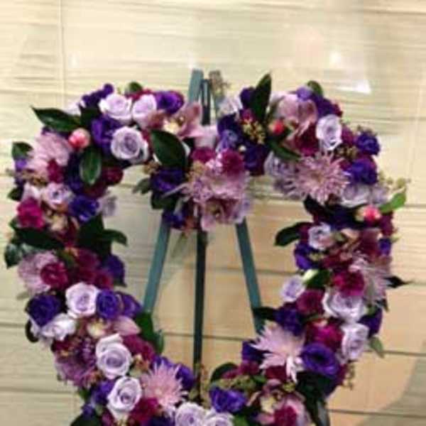 Heart-shaped floral wreath on an easel with purple and pink flowers