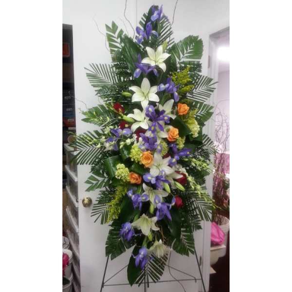 Tall floral standing spray with white lilies, purple orchids, and orange roses