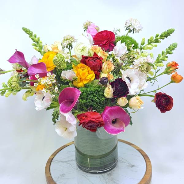 Colorful mixed bouquet in a glass vase with calla lilies and roses