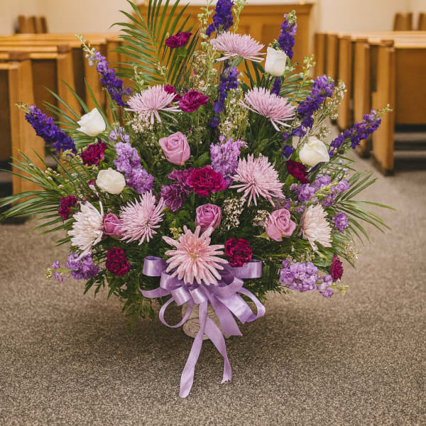 Large purple and pink floral arrangement in a church aisle