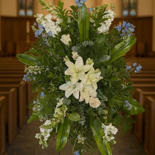 Large floral standing spray with white lilies and blue accents