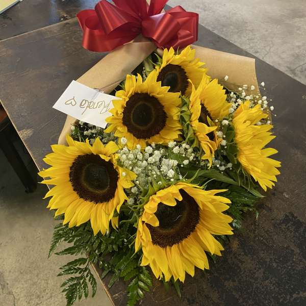 Bouquet of sunflowers wrapped in brown paper with a red ribbon bow