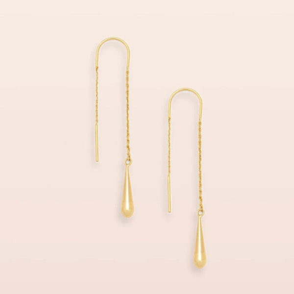 Pair of gold threader earrings with teardrop dangles on a light background