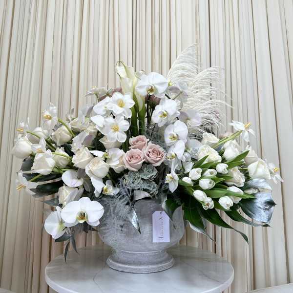 Large white floral arrangement in a gray urn vase