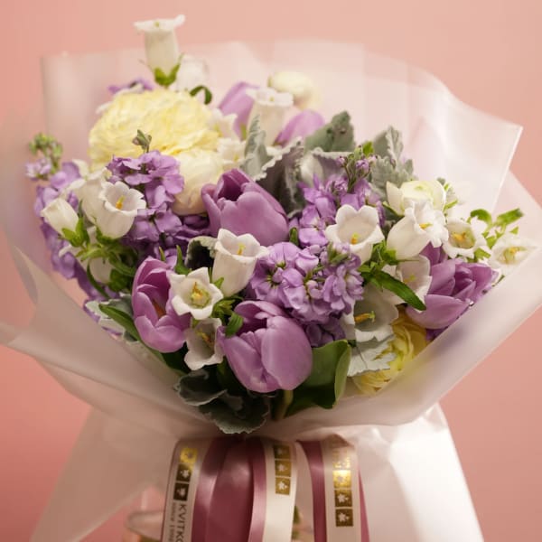 Bouquet of purple and white flowers wrapped in translucent paper