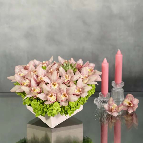 Pink orchid arrangement in a white box with two pink candles