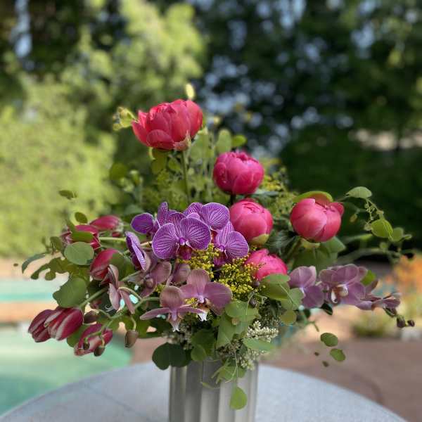 Pink and purple flowers arranged in a silver vase