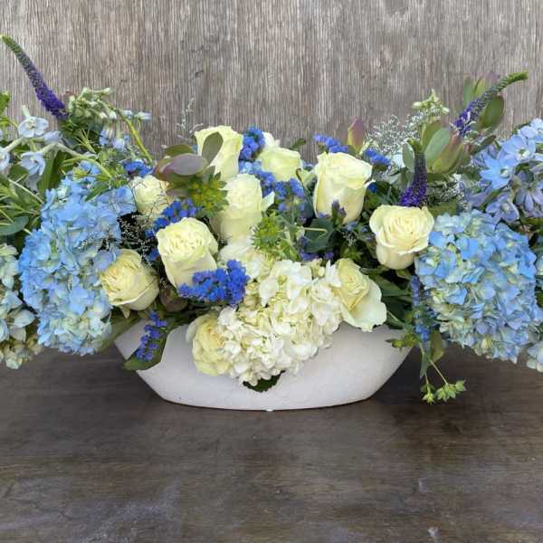 Blue and white floral arrangement in a white bowl vase