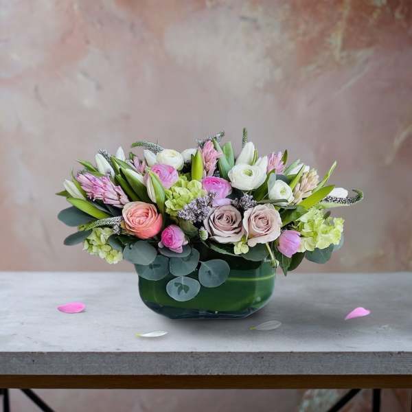 Pink and white mixed flower arrangement in a green glass vase
