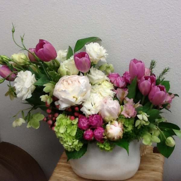 Pink tulips and white flowers arranged in a white vase
