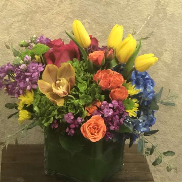 Colorful mixed flower arrangement in a square glass vase