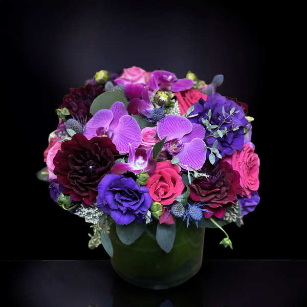 Purple and pink floral arrangement in a dark green vase