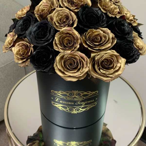 Black and gold bouquet of roses in a tall round box