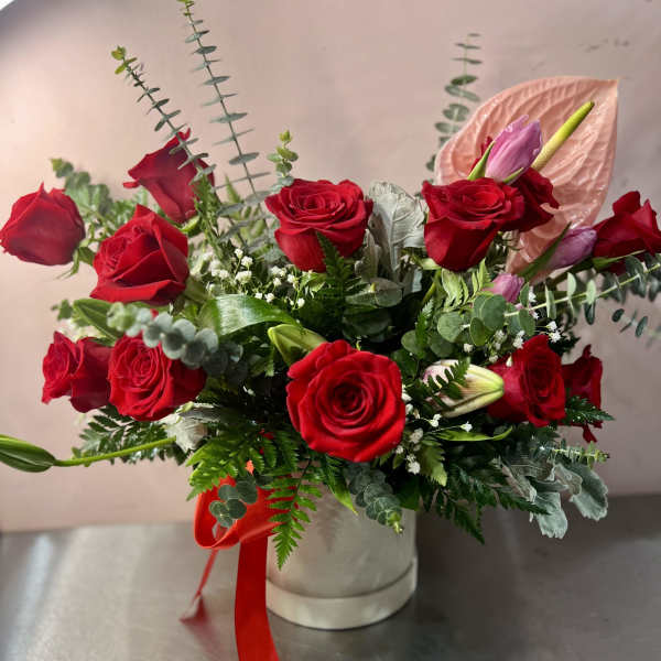 Red roses and pink lilies in a white hat box with a red ribbon