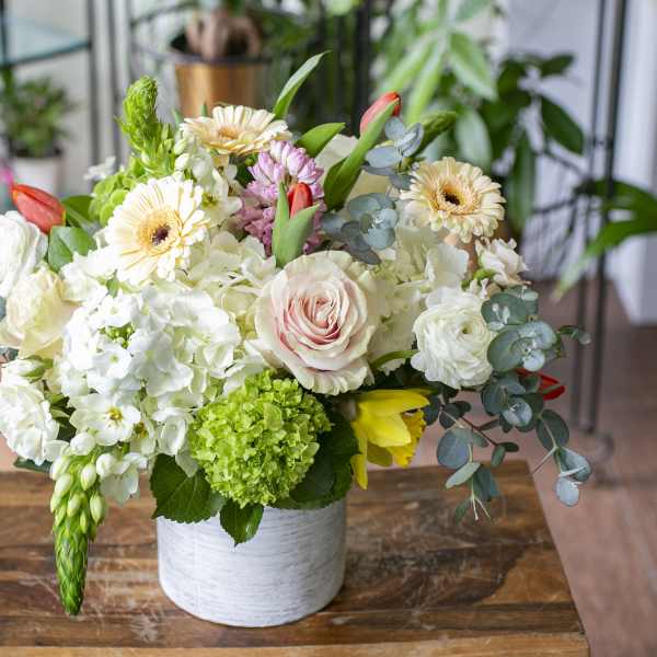 Mixed bouquet in a white vase with white, pink, and yellow blooms