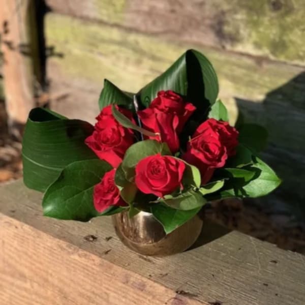 Red roses arranged in a small gold vase
