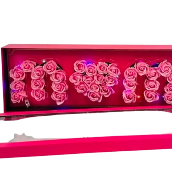 Pink box of roses spelling MOM with a heart shape in the center and small colored lights inside