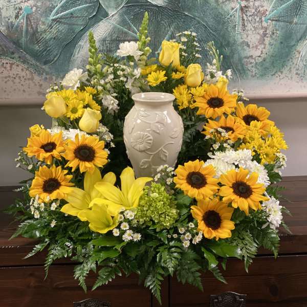 Yellow sunflowers and roses arranged around a white vase