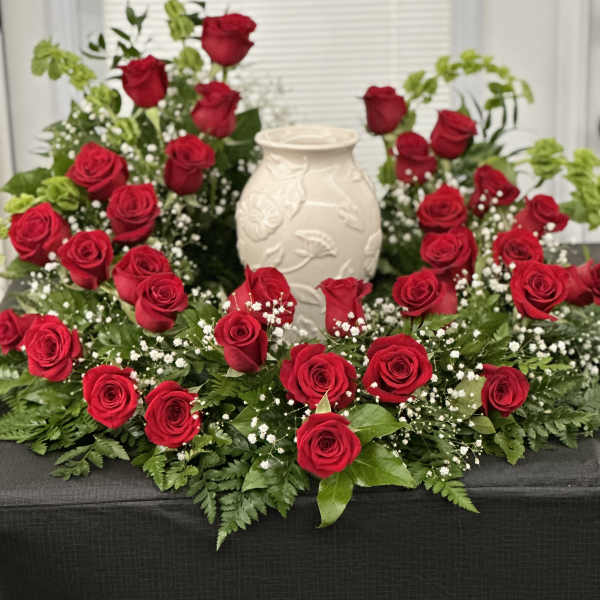 Red roses arranged around a white vase centerpiece