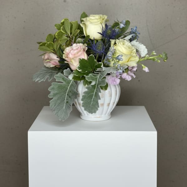 Mixed bouquet in a white vase with pale roses and blue thistle