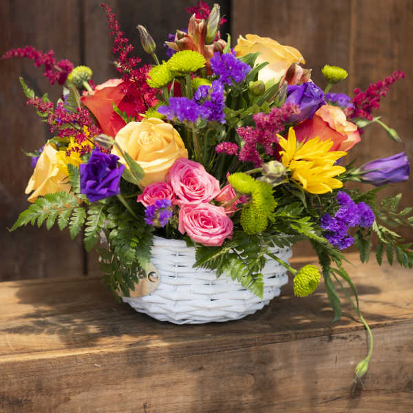 Colorful mixed flower arrangement in a white wicker basket