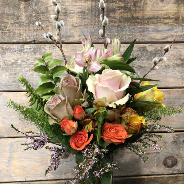 Mixed bouquet of roses, lilies, and pussy willow in a glass vase