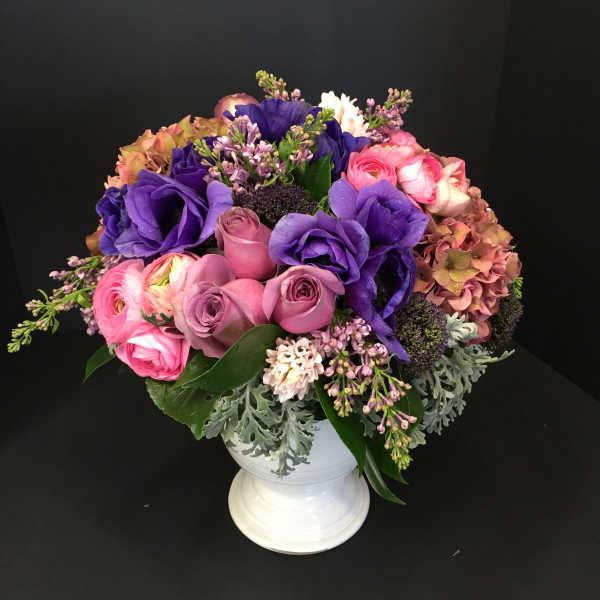 Pink and purple mixed bouquet in a white pedestal vase