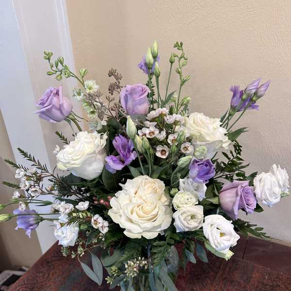 Lavender and white bouquet of roses and lisianthus in a glass vase