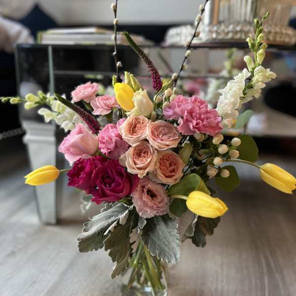 Mixed pink and yellow flower arrangement in a clear glass vase