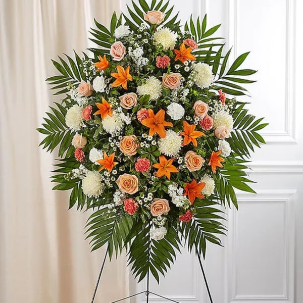 Large standing floral spray with peach roses, orange lilies, and white blooms
