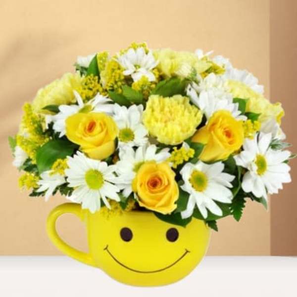 Yellow and white flower arrangement in a smiley-face mug