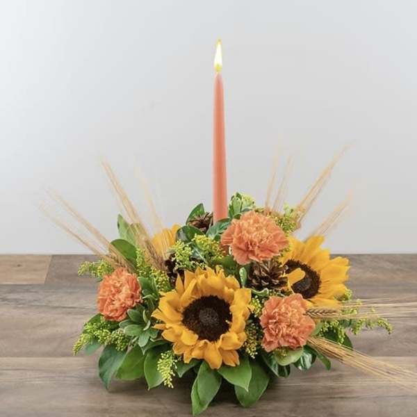 Sunflower and carnation centerpiece with a tall coral taper candle