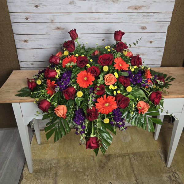 Large arrangement of red roses, orange gerberas, and purple flowers on a table