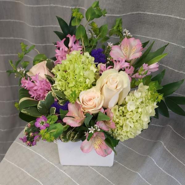 Mixed bouquet in a white square vase with pink and cream flowers