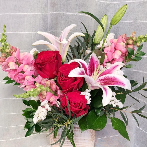 Bouquet of red roses and pink lilies in a wooden box