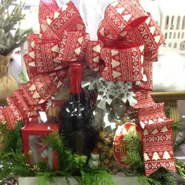 Christmas gift basket with wine, snacks, and red patterned bows