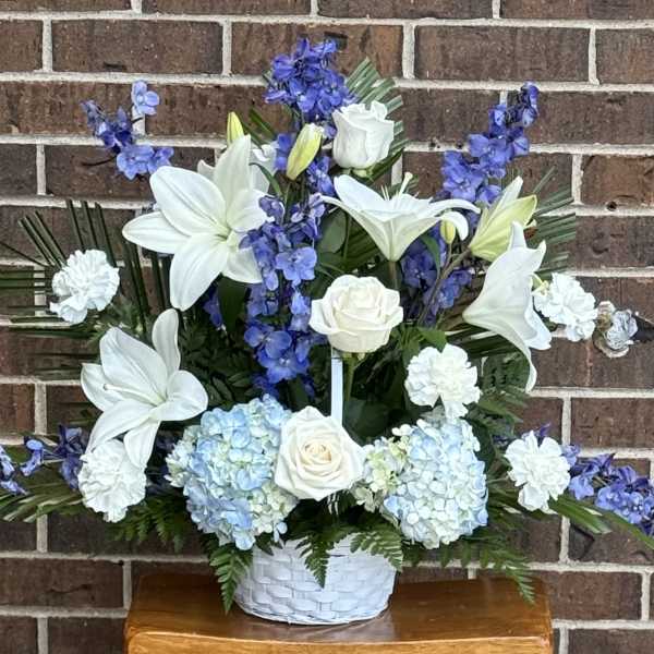 White lilies and roses with blue flowers in a white basket