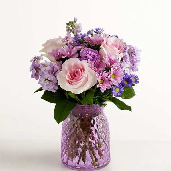 Pink and lavender bouquet in a purple glass vase