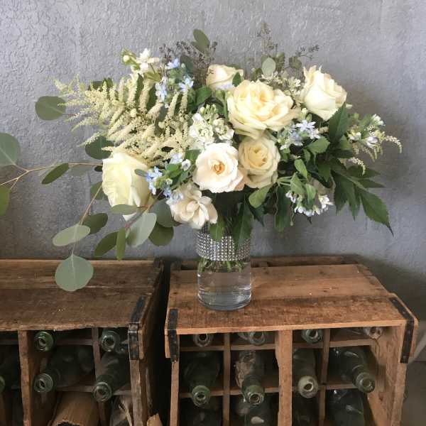 Cream rose bouquet in a clear glass vase with mixed greenery