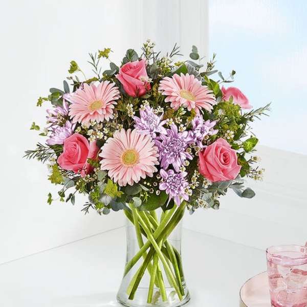 Pink roses and daisies in a clear glass vase