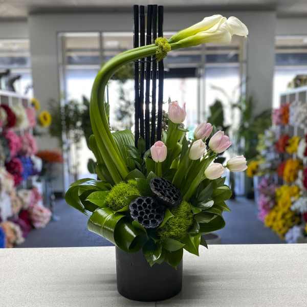 Modern floral arrangement with pink tulips and a white calla lily in a black vase