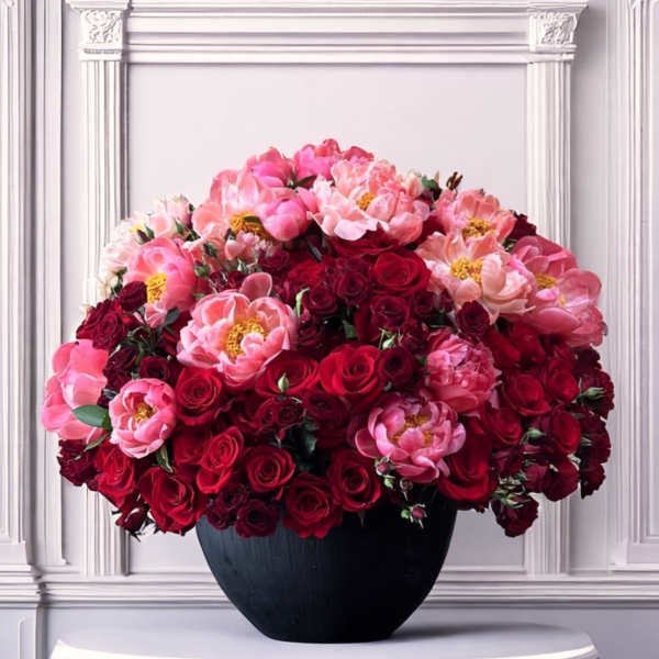 Large bouquet of pink and red flowers in a black vase