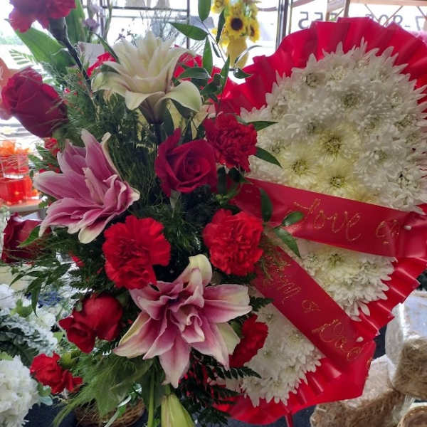 Red and white floral standing arrangement with lilies, roses, and chrysanthemums