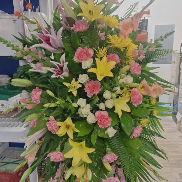 Tall standing floral spray with lilies, carnations, and pink snapdragons